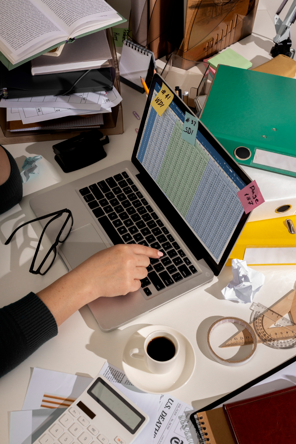 messy desk woman's hand on an opened laptop